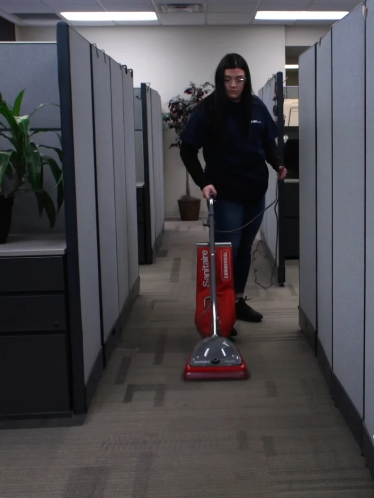 Commercial cleaner vacuuming carpet in an office cubicle area